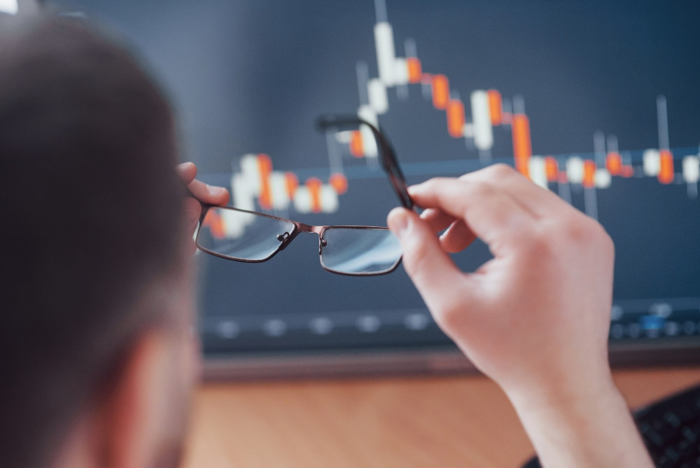 analyzing-data-close-up-young-businessman-who-holds-glasses-looks-gff-while-working-creative-office สรุป การเป็นเทรดเดอร์รายวัน ดีหรือไม่